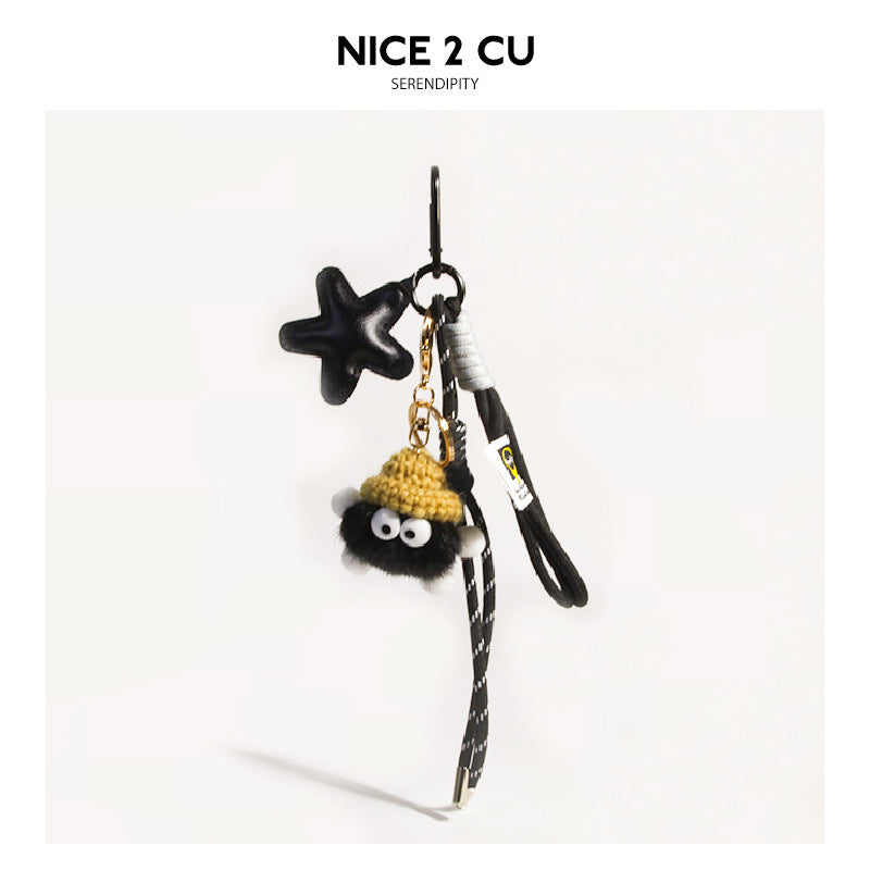 Deep matte black fluffy coal-ball bag charm with yellow knit hat, black star charm, dark braided cord, and gold swivel clip