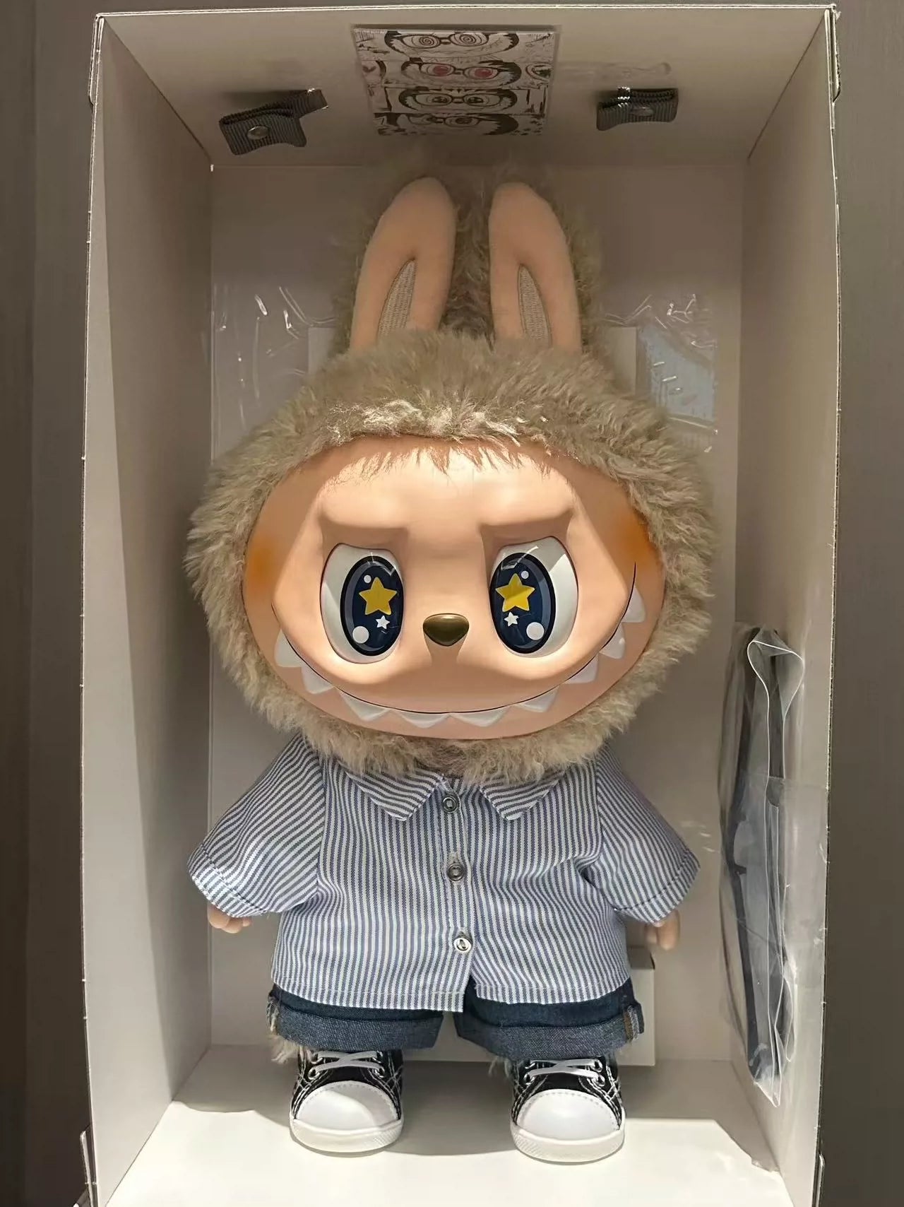 The POP MART THE MONSTERS – FLIP WITH ME 38cm Labubu Vinyl Plush Doll, dressed in a sailor shirt and denim, is displayed in a box—perfect for fans of designer dolls and collectible fashion art.