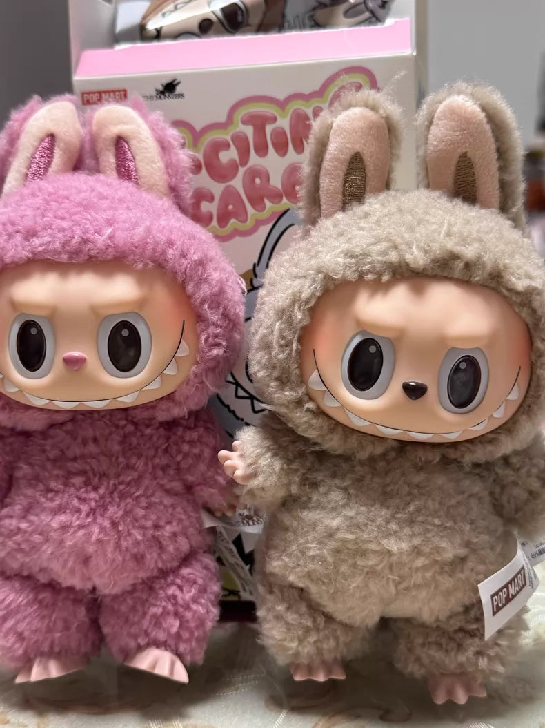 Two POP MART Labubu "Toffee" Plush Keychain collectibles by Kasing Lung—standing brown bunny dolls with big eyes, wide grins, and bunny-ear hoods—stand before a colorful box to charm your collection.