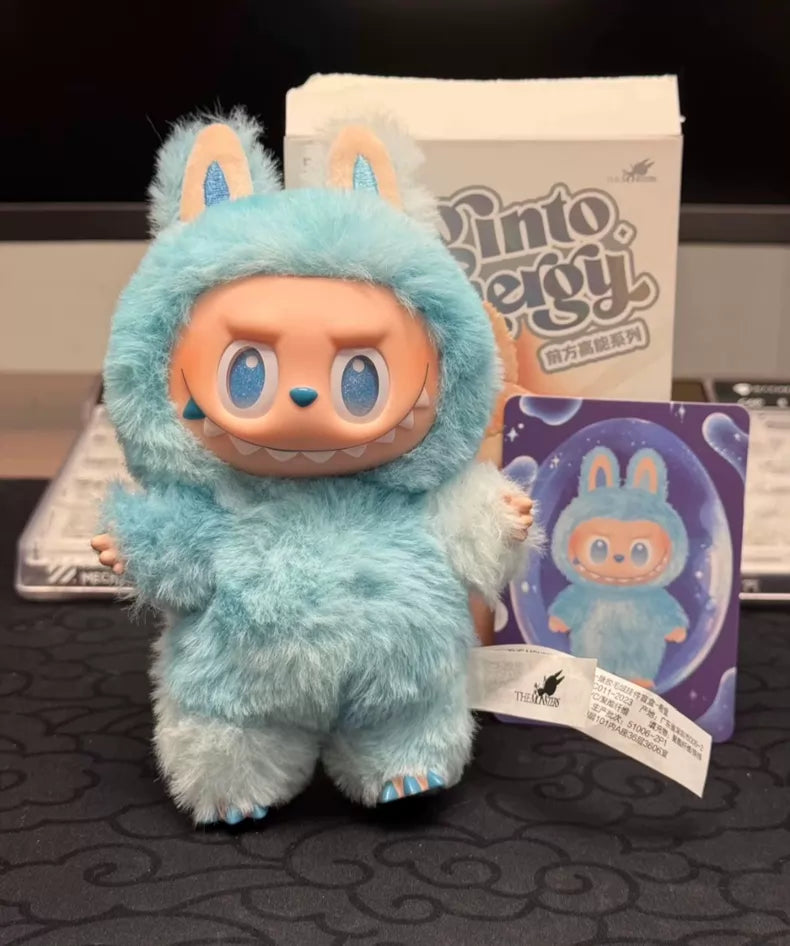 The POP MART Labubu “Hope” Plush Keychain from The Monsters “Big Into Energy” series features a big-headed labubu in a sky-blue bunny costume with large ears and teeth, standing by its packaging—an ideal collectible or bag charm.