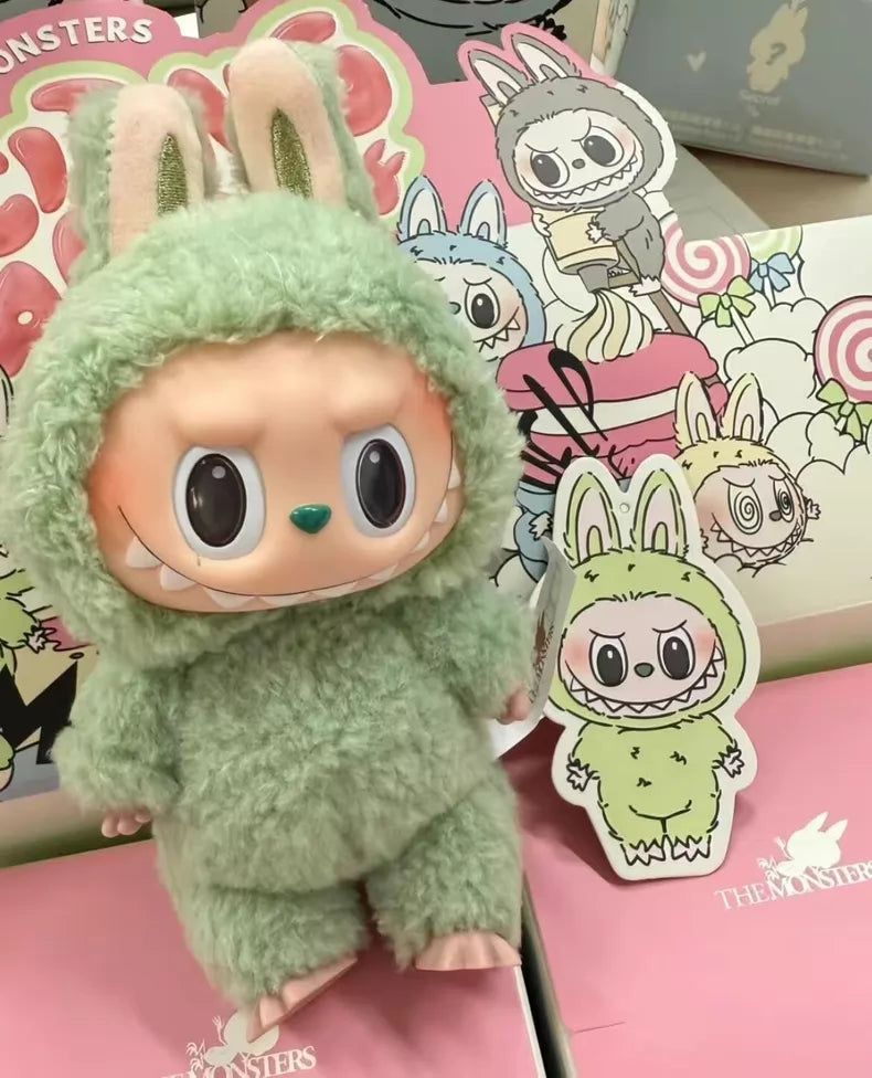 The Labubu “Green Grape” Plush Keychain from POP MART features a standing green bunny with large eyes, and comes with a cardboard cutout and illustrated packaging showcasing other The Monsters characters.