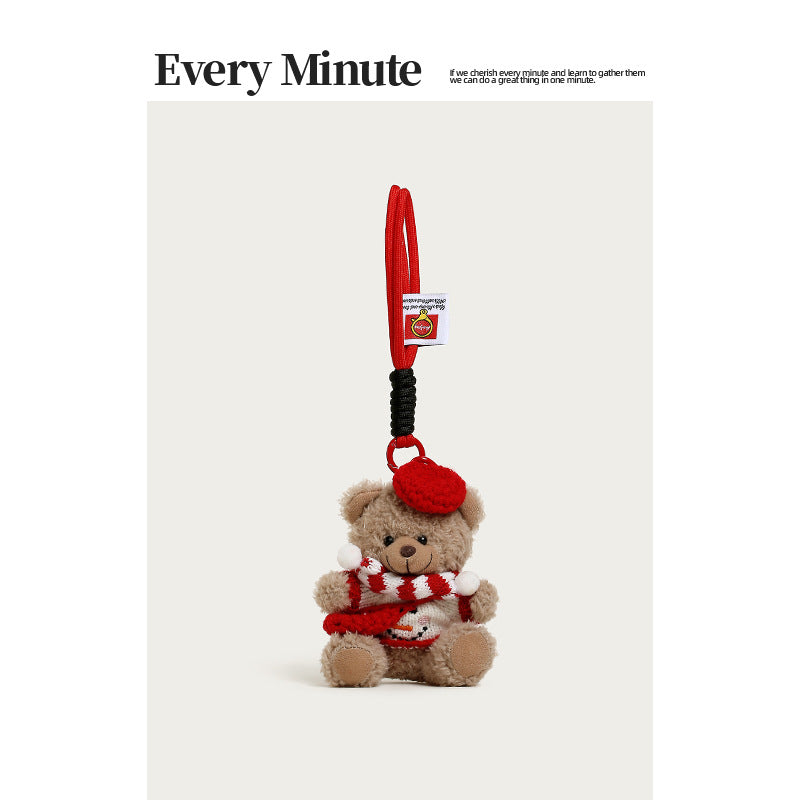 Brown plush bear charm with red beret, red-and-white striped scarf, and snowman sweater design
