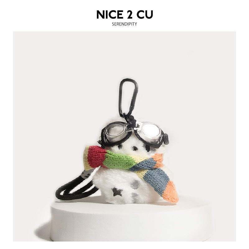 White fluffy dog plush charm wearing black goggles and a multicolor rainbow knit scarf with carabiner clip