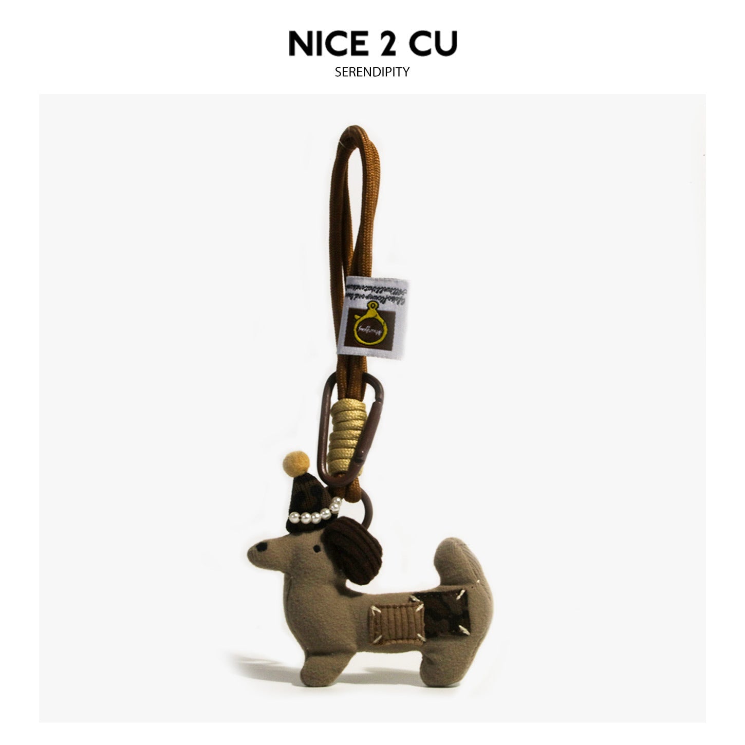 Coffee-brown plush dog bag charm with pearl-trimmed dark hat, patch-style details, and braided brown cord loop