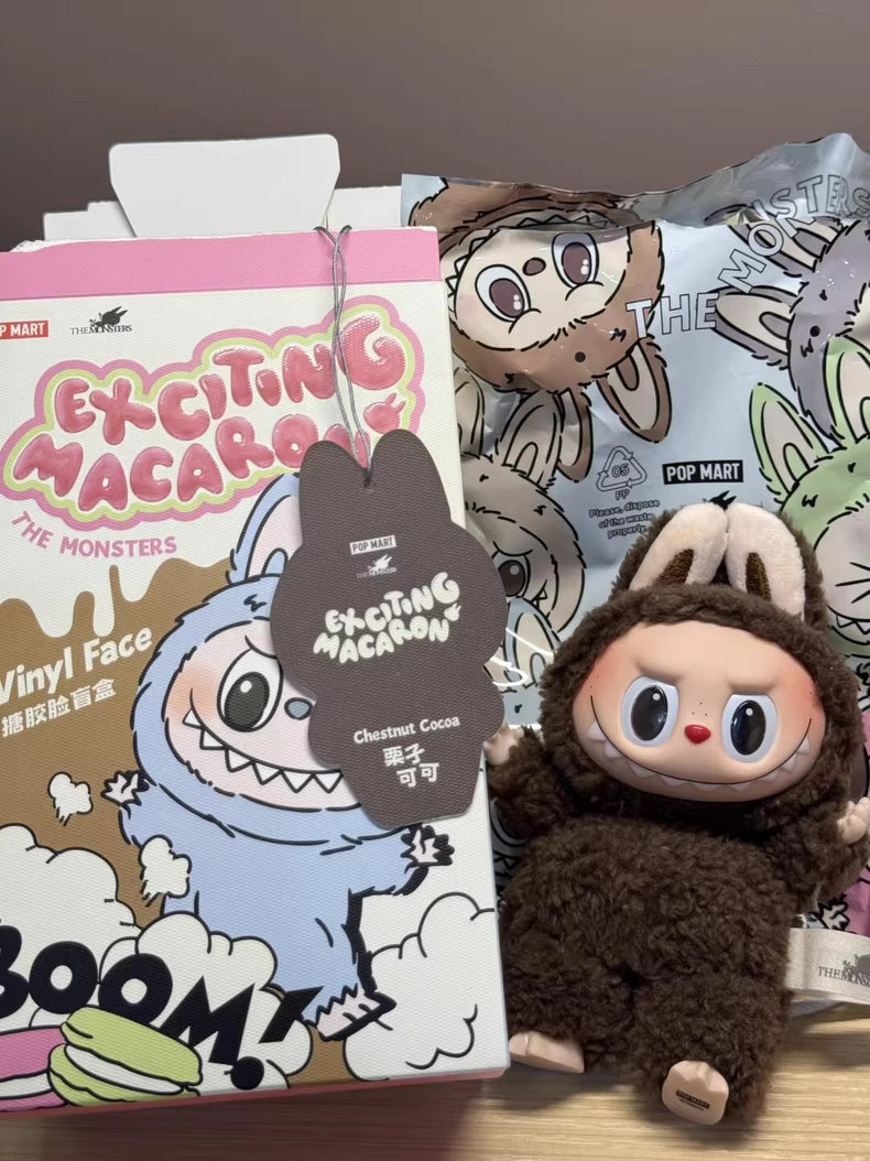 The Labubu Secret Edition “Chestnut Cocoa” Plush Keychain – Pop Mart Standing Brown Bunny by Kasing Lung is a charming POP MART collectible, shown in front of an Exciting Macaron box with playful cartoon monster illustrations.