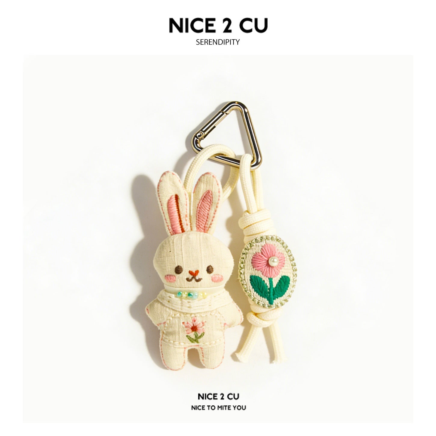 Cream knitted bunny keychain charm in pink outfit with floral embroidery and gold-tone carabiner clip