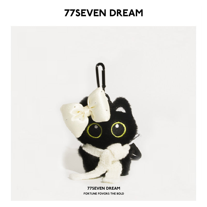 Black cat plush keychain with large yellow-outlined eyes, white scarf, and oversized white bow