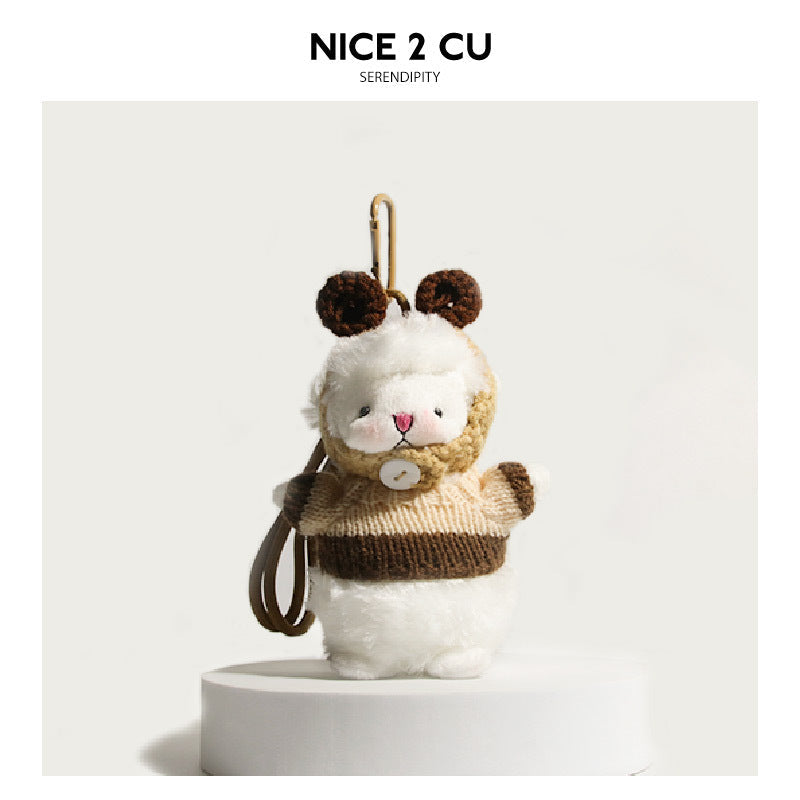 White fluffy lamb plush charm dressed in a brown and beige knitted outfit with dark brown ear accents and brown loop cord
