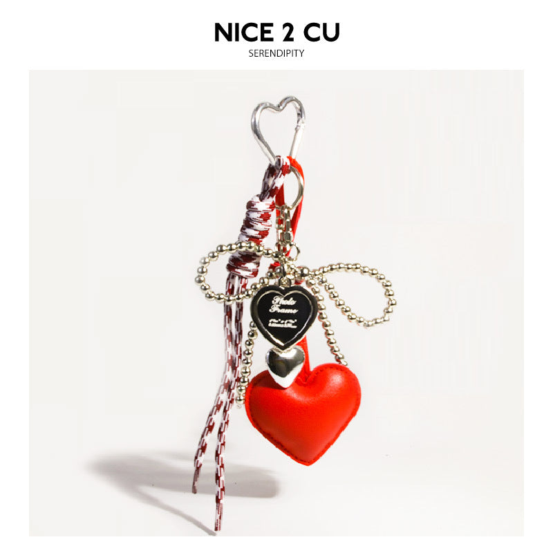 Red heart bag charm with silver heart carabiner, gold ball chain bow, and small black heart tag