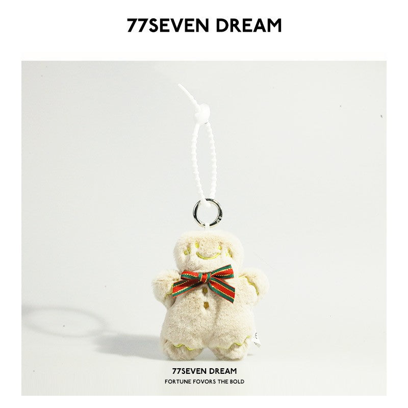 Cream gingerbread person plush charm with stitched face, red and green bow, and white hanging cord on metal ring