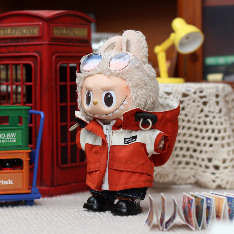 The ZoDoll Labubu Red Explorer Jacket Outfit Set with Gloves and Boots plush stands indoors near a red phone booth, lamp, stacked crates, and scattered cards, wearing bunny ears and sunglasses.