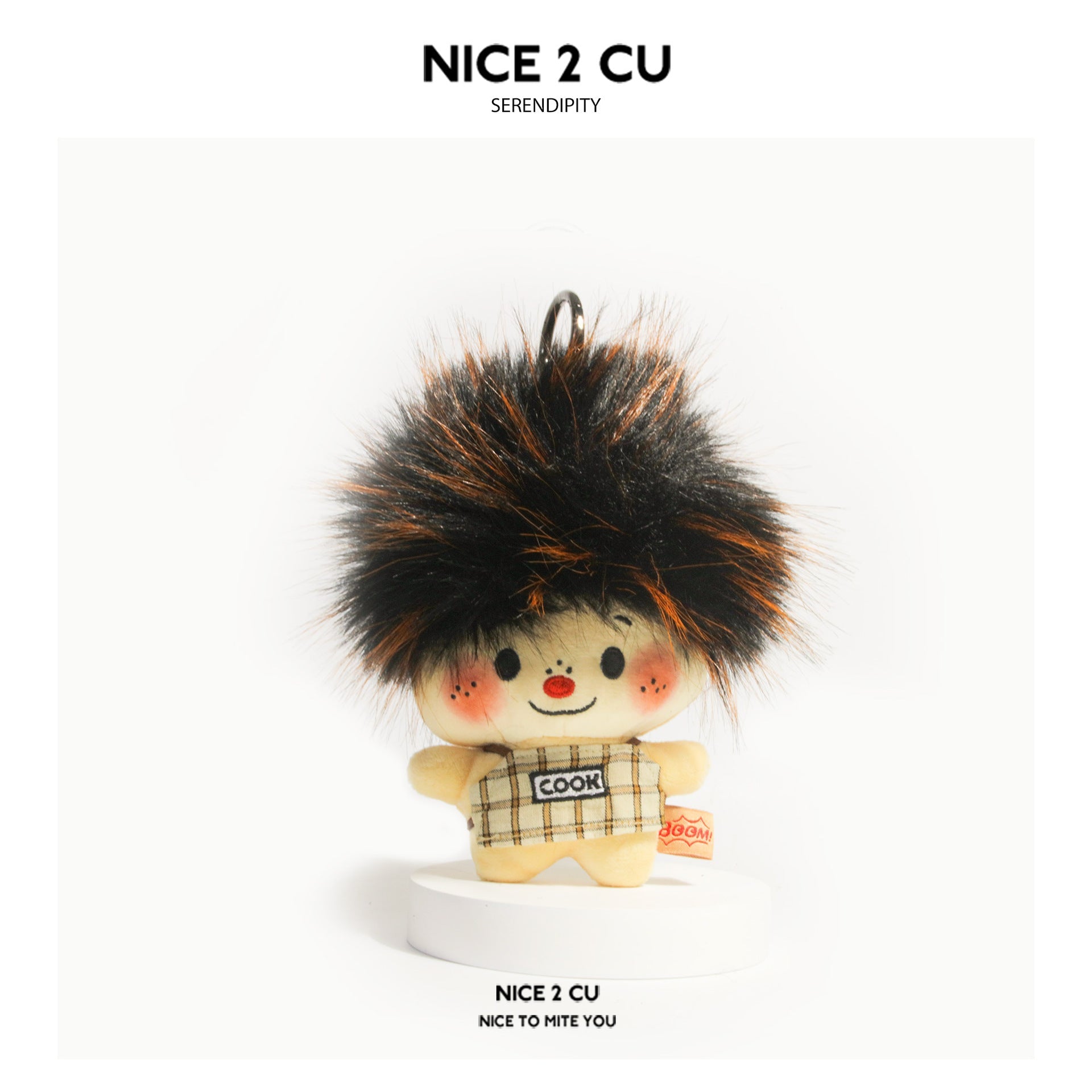 Almond-tone scorched chef plush keychain with frizzy hair, tan plaid COOK apron, and smiling expression