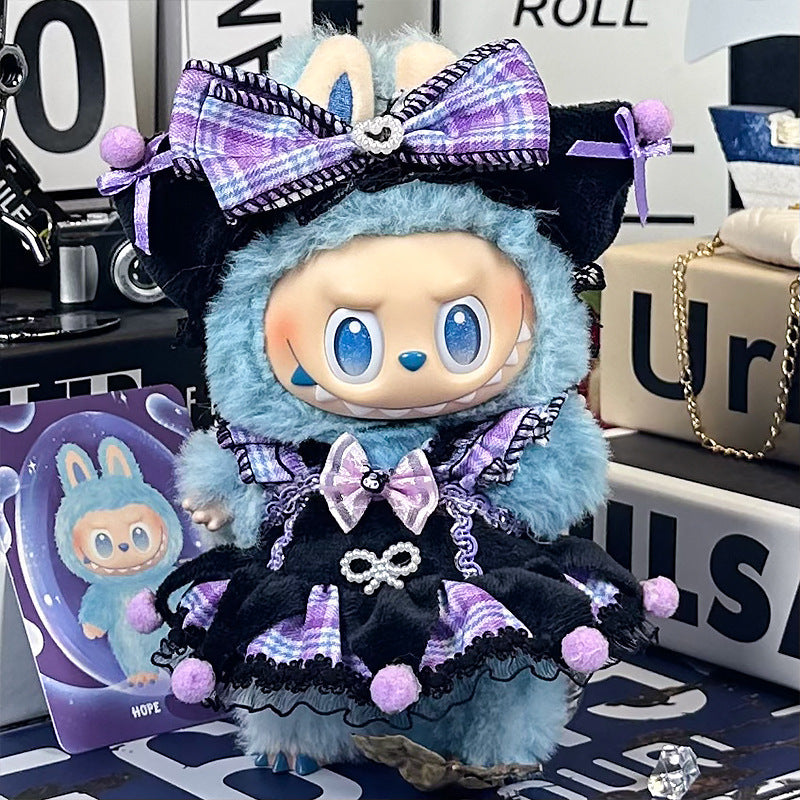 A ZoDoll Labubu plush in a Gothic Lolita purple plaid dress with black lace and pom-poms stands on a table, with boxes and cards in the background.