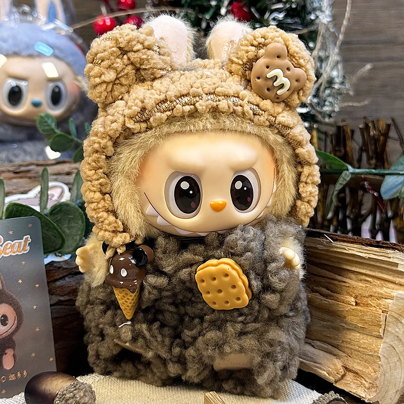 The ZoDoll Labubu Cookie Bear Fluffy Plush Onesie features a brown teddy hoodie outfit, large round eyes, and cute cookie and ice cream details. This collectible plush doll stands among plants and wooden objects.