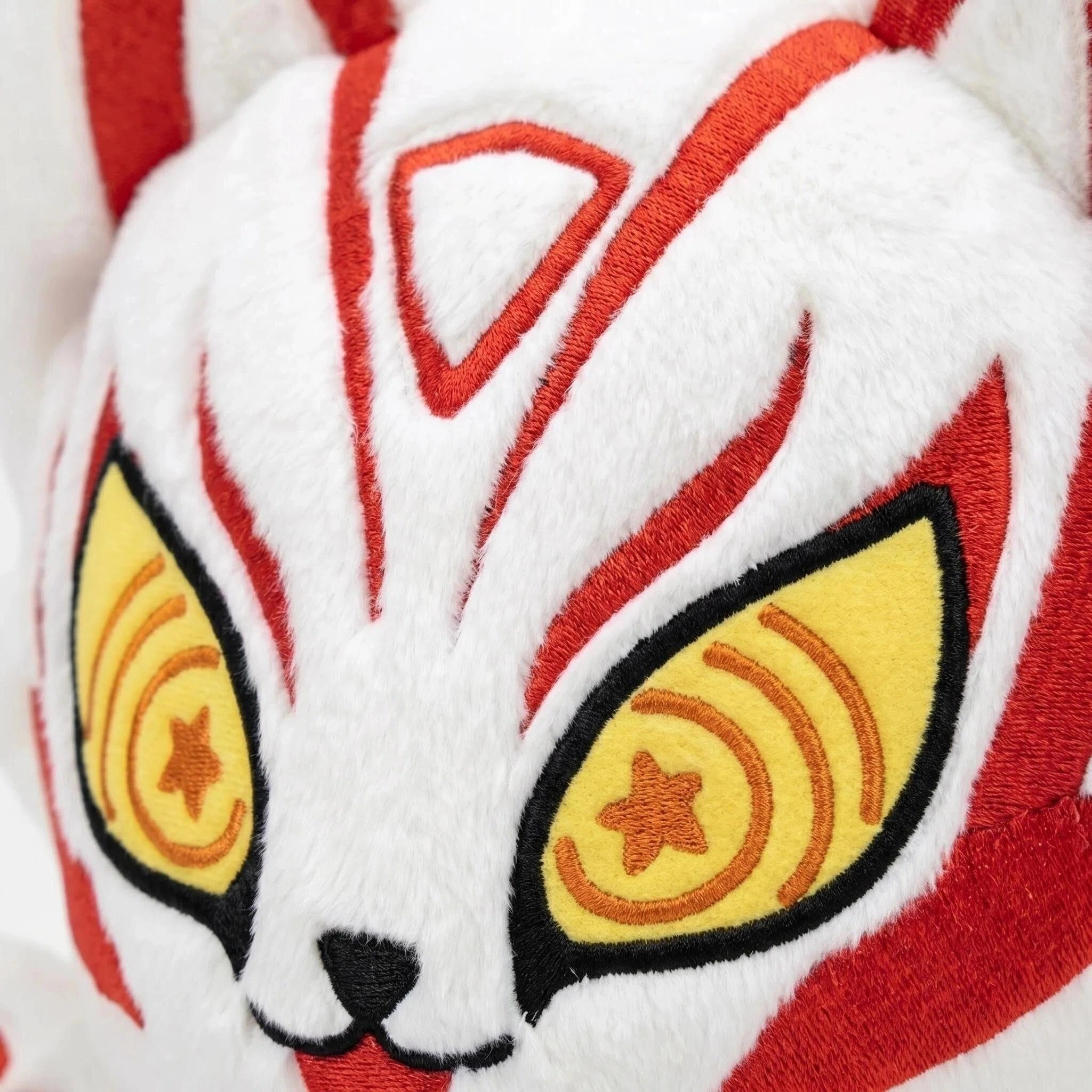 Close-up of the ZoDoll White Fox Plush Toy, a cute plush doll with white fur, red markings, big ears, and large yellow eyes featuring star patterns.