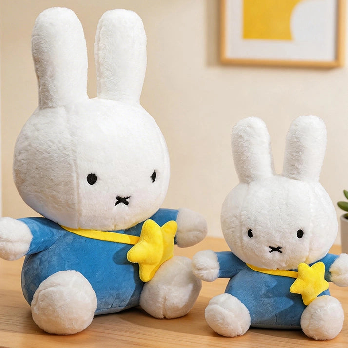 Two ZoDoll Miffy Bunny Plush Dolls (30cm-80cm), white and dressed in blue with yellow star accents, sit on a wooden surface with framed art and a plant in the background.