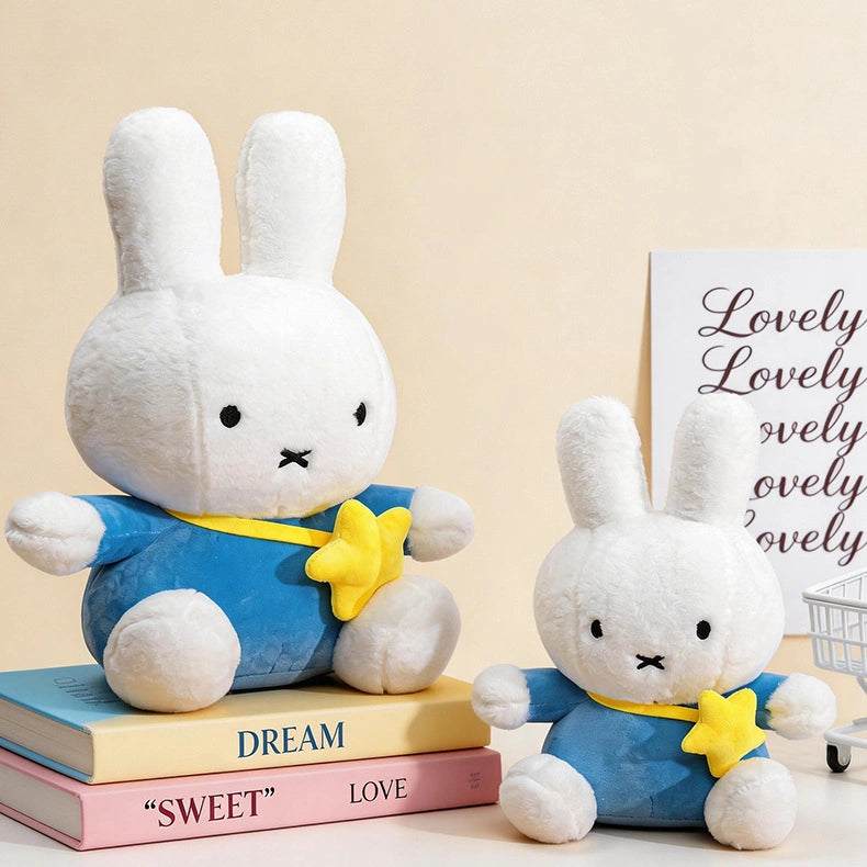 Two ZoDoll Miffy Plush Toys—Miffy Bunny Plush Dolls (30cm-80cm) in white with blue outfits and yellow stars—sit on pastel books, with a decorative "Lovely" sign in the background. Available in 2 colors.