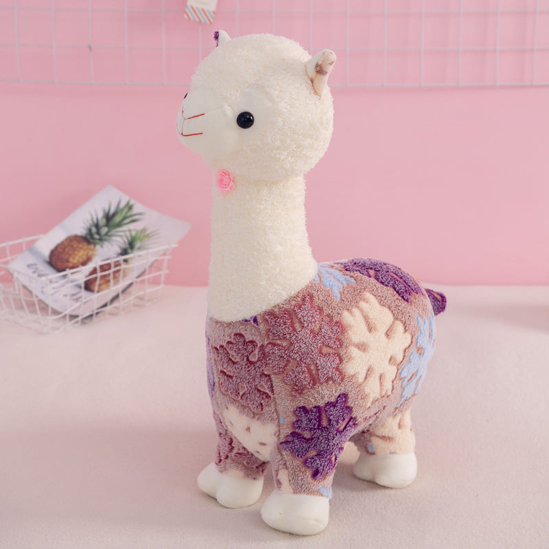 The ZoDoll Flower Alpaca Plush Toy features a soft, multicolored stuffed alpaca with a white head, displayed on a light surface with a wire basket and card in the background.