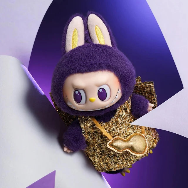 The POP MART Labubu × PRONOUNCE Wings of Fortune Limited Edition Designer Plush Vinyl Toy features a round face, purple eyes, gold-eared purple bunny suit, and gold outfit, set against a chic purple and white background.