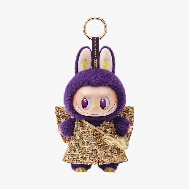 A POP MART Labubu × PRONOUNCE Wings of Fortune limited edition plush vinyl keychain features a doll in a purple fuzzy bunny suit with tweed dress and gold purse, inspired by the collectible art toy, shown on a white background.