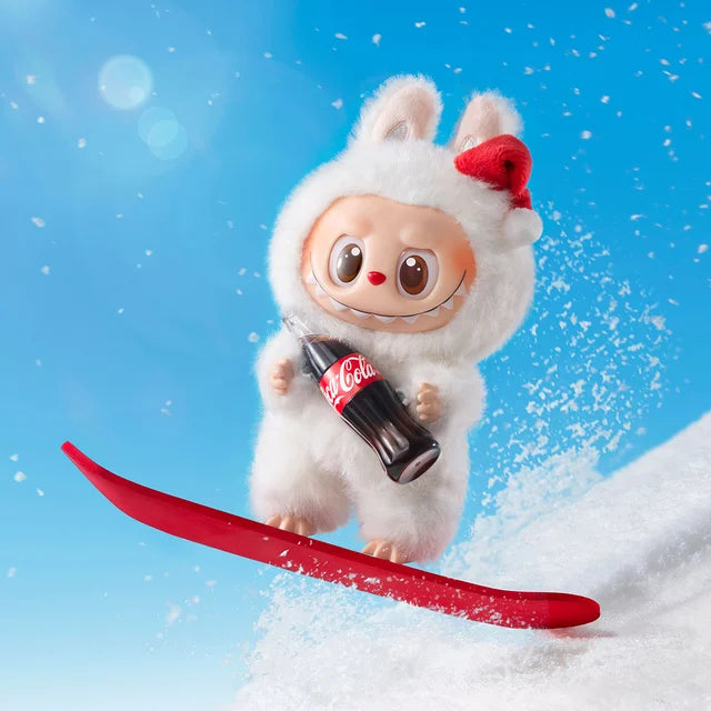 A cartoon character in a white bunny costume snowboards downhill with a Coke bottle, resembling the POP MART Labubu Coca‑Cola Surprise Shake Plush Keychain – Christmas Bunny Edition Vinyl Collectible, against a bright blue sky.