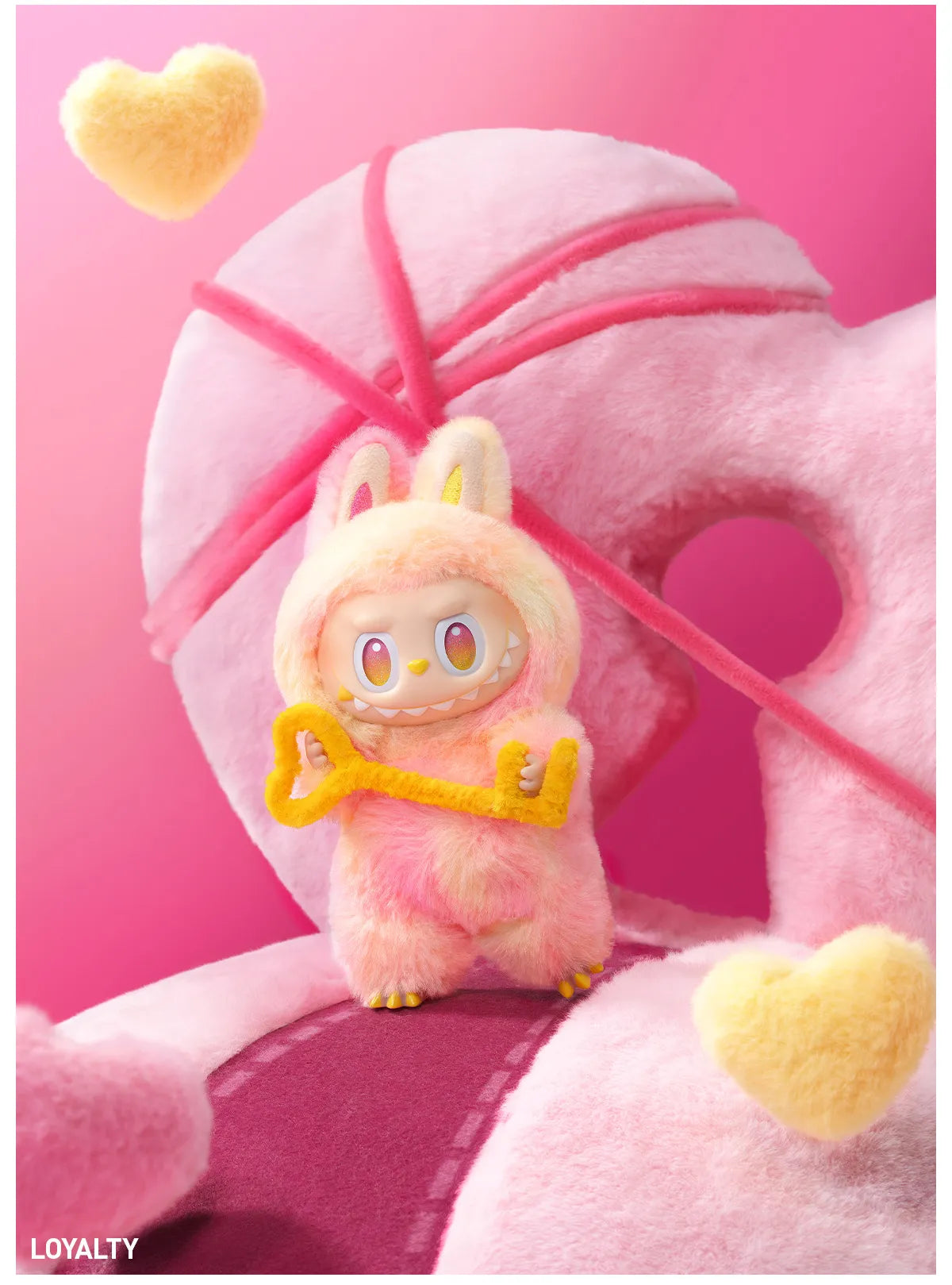 The POP MART Labubu “Loyalty” Plush Keychain from the Monsters “Big Into Energy” Series features a smiling tie-dye bunny with heart accents, standing before a pink heart and the word LOYALTY at the base.