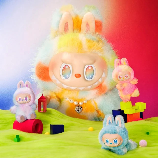 A 37cm POP MART Labubu Big into Energy Series Plush Doll and three smaller THE MONSTERS toys are displayed on a fuzzy green surface with colorful blocks, set against a vibrant gradient background.