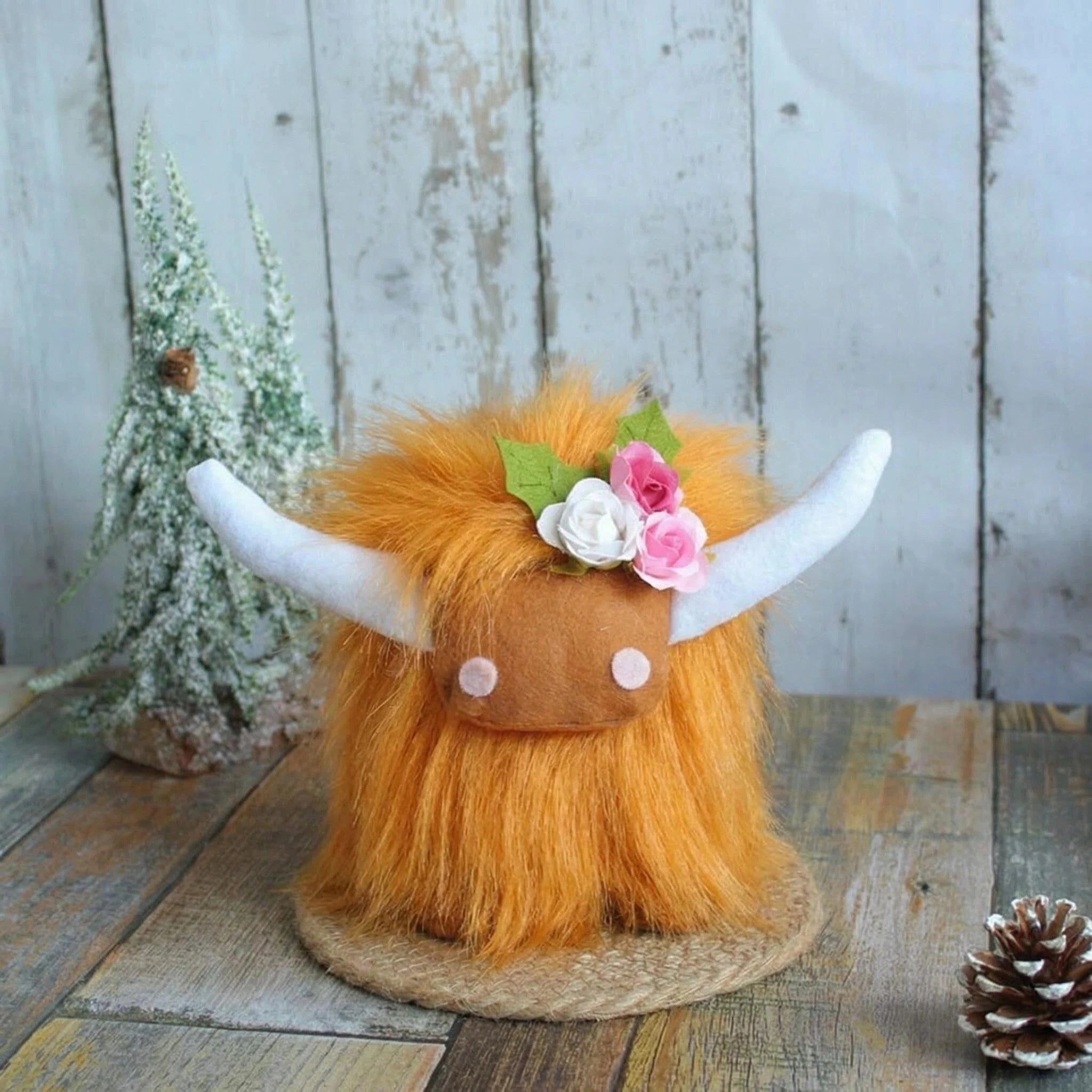 The ZoDoll Highland Cow Plush Toy with Pink Bow features soft long hair and comes in 6 colors. Placed beside a pine tree, this adorable plush adds cozy whimsy to any space.
