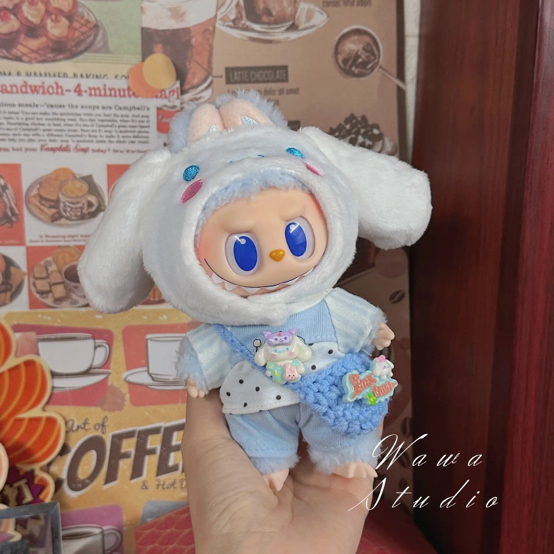 A ZoDoll Labubu Sanrio Doll wears a Hello Kitty style outfit from the Outfit Collection, posed in front of a vintage-themed coffee shop, highlighting kawaii fashion.