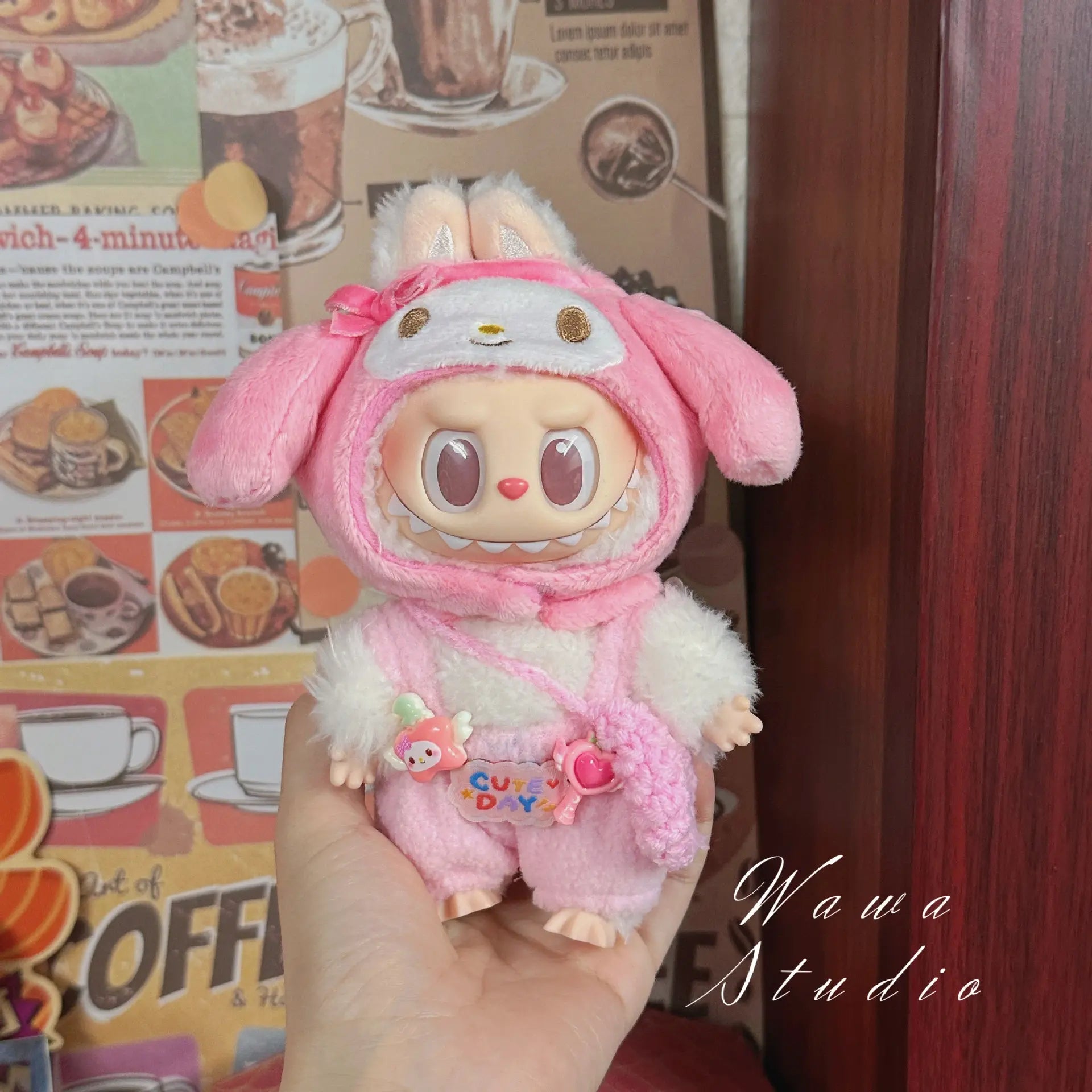 A ZoDoll Labubu plush doll wears a Hello Kitty-style outfit from the Sanrio Doll Clothes Set, styled in kawaii fashion and posed before a wall decorated with food posters.
