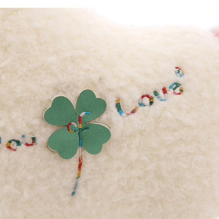 A green paper clover with the letter "f" is attached to the soft white surface of the ZoDoll Cute Alpaca Plush Toy, next to colorful embroidered "love" text.
