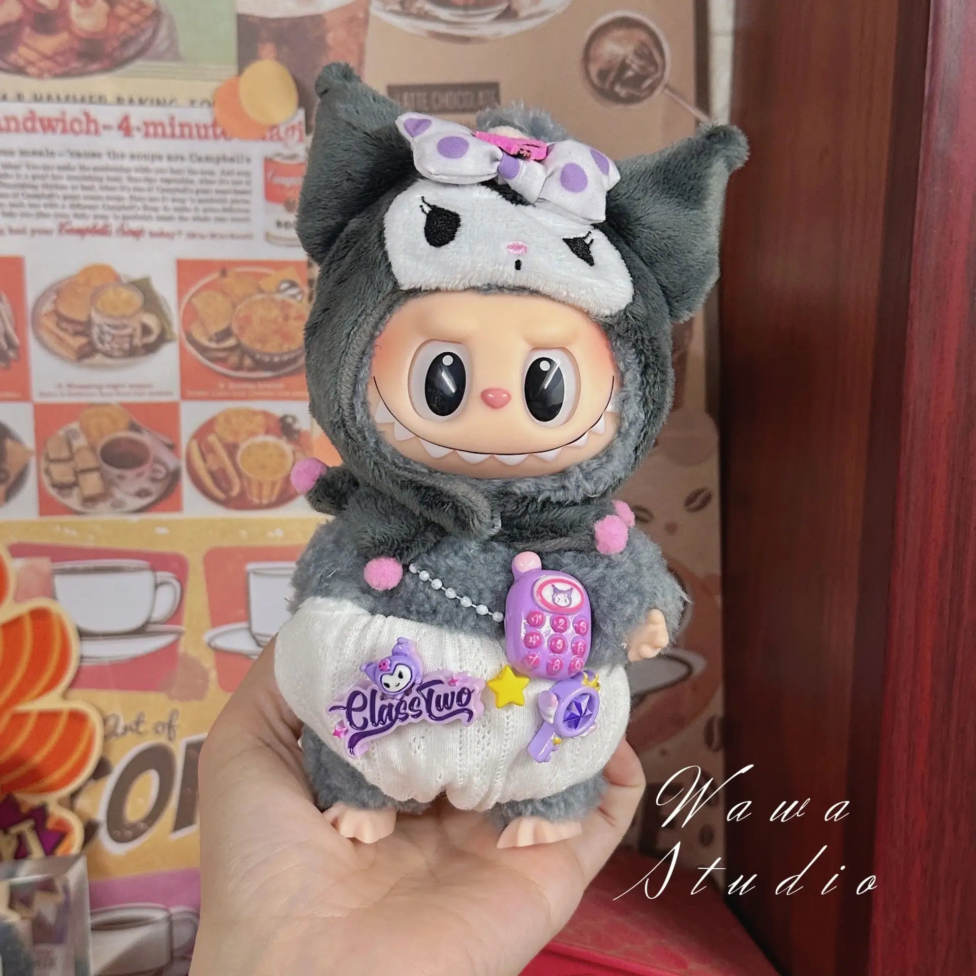 A hand holds a ZoDoll Labubu Sanrio Doll in a Hello Kitty-style outfit, featuring a bow and pouch. Retro food posters in the background highlight trendy fashion from the Labubu Sanrio Doll Clothes Set – Hello Kitty Style Outfit Collection.