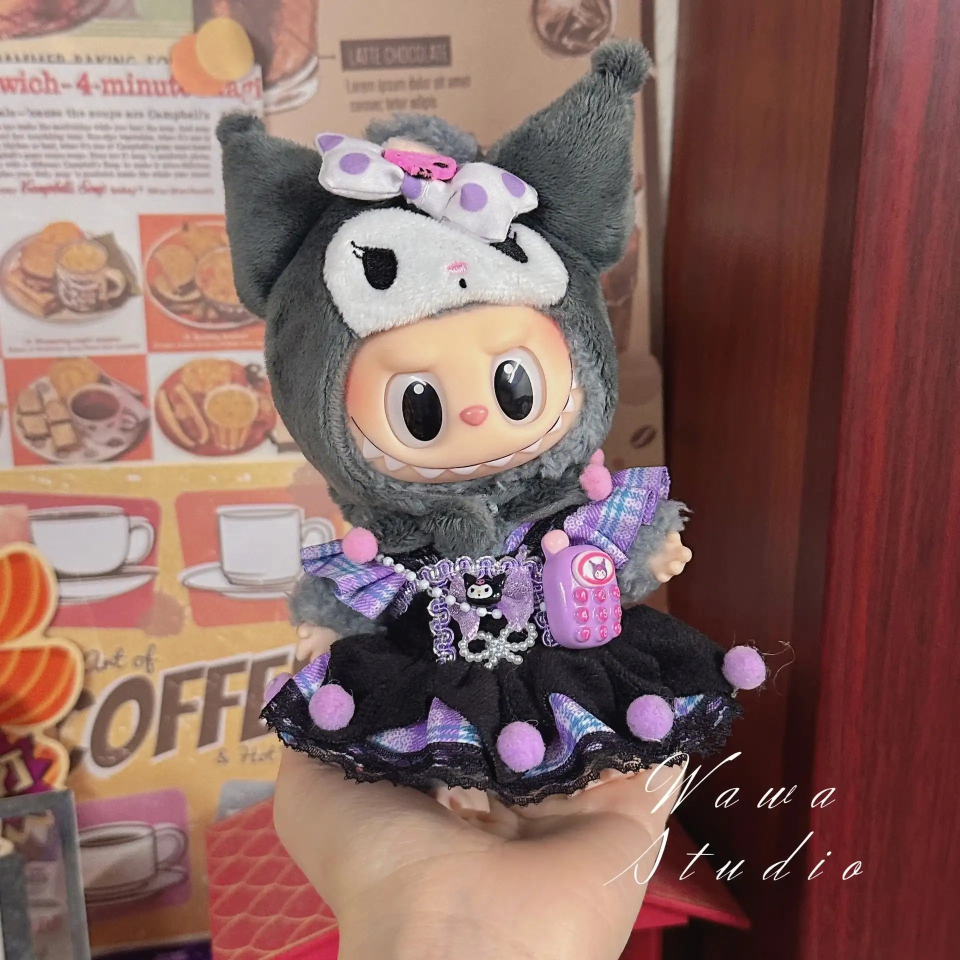 The ZoDoll Labubu Sanrio Doll Clothes Set features a Hello Kitty style outfit in black and purple with animal details, a bow, and a small pink phone, displayed against a coffee-themed background.