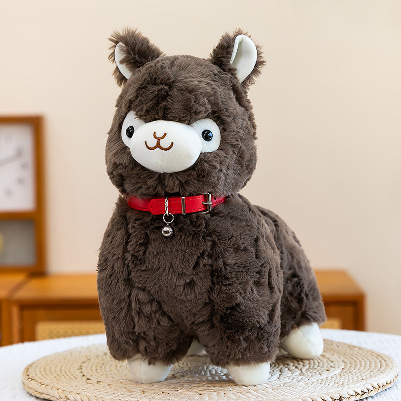 The ZoDoll Cute Alpaca Plush Toy is a soft stuffed alpaca doll with brown fur, a white face and ears, plus a red collar with a tiny bell. It’s perfect for cuddling and looks adorable sitting on any woven mat.