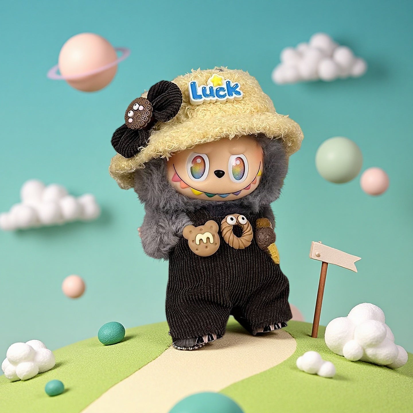 The ZoDoll Labubu Doll features a gray fuzzy hoodie, corduroy overalls, and a yellow "Luck" bucket hat, posed on a pastel landscape with clouds and planets in the background.
