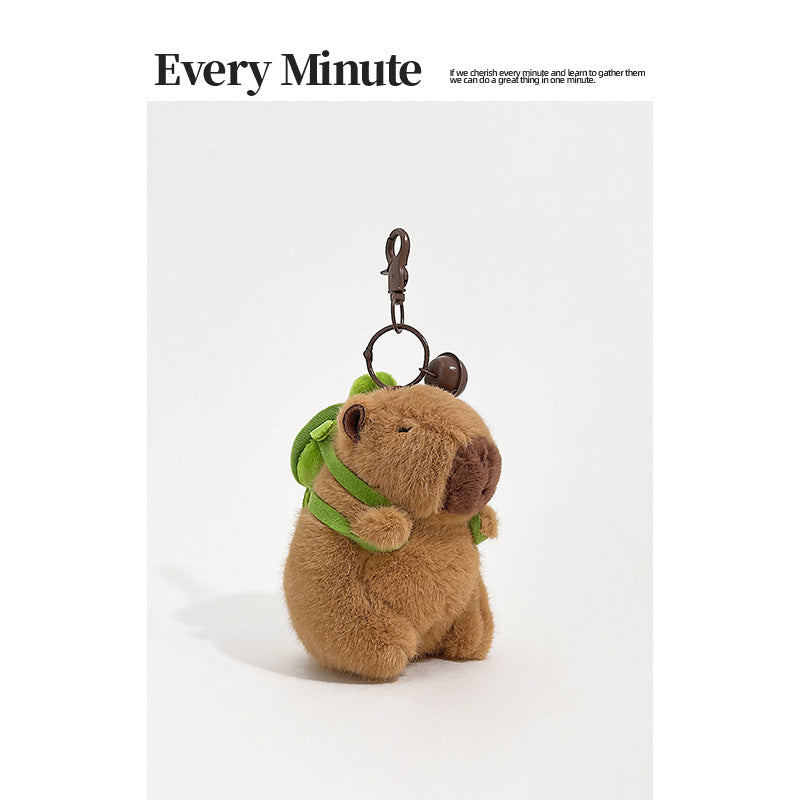 Brown plush capybara keychain wearing a small green turtle-shaped backpack with metal swivel clasp