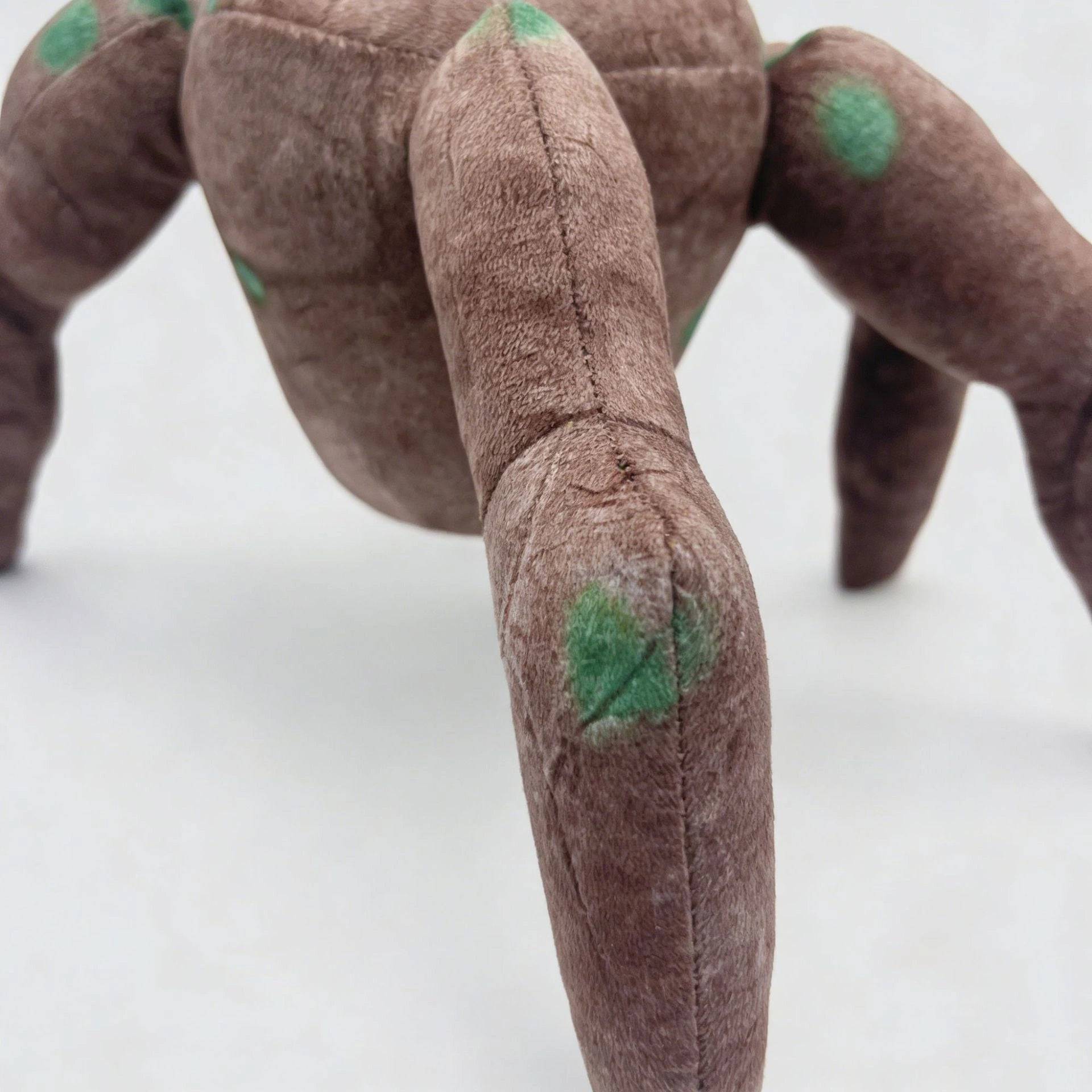 A close-up of the ZoDoll Rocky Plush Project Hail Mary 20.2cm Alien Companion Stuffed Toy showcases its four legs and green spots, inspired by Project Hail Mary, displayed on a plain white surface.
