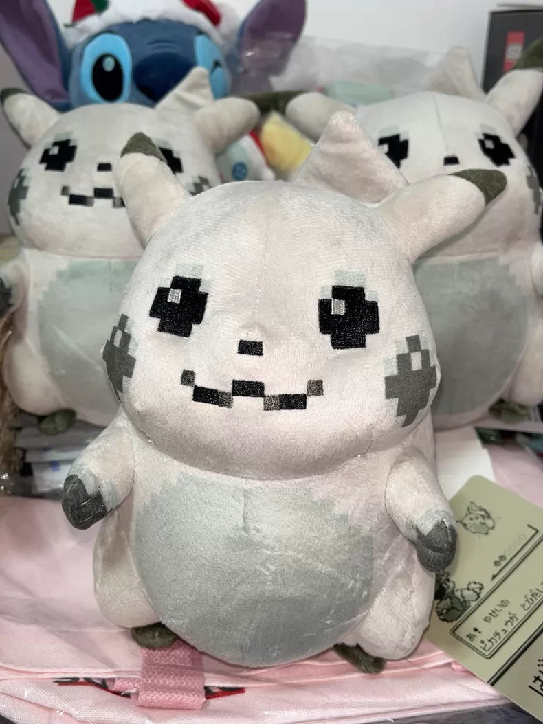 A ZoDoll Retro 8-Bit Pikachu of Beginnings Plush—Classic Chunky Pokémon 30th Anniversary Pikachu—stands with two similar plush toys on the table, showcasing its gray body and pixelated black features.