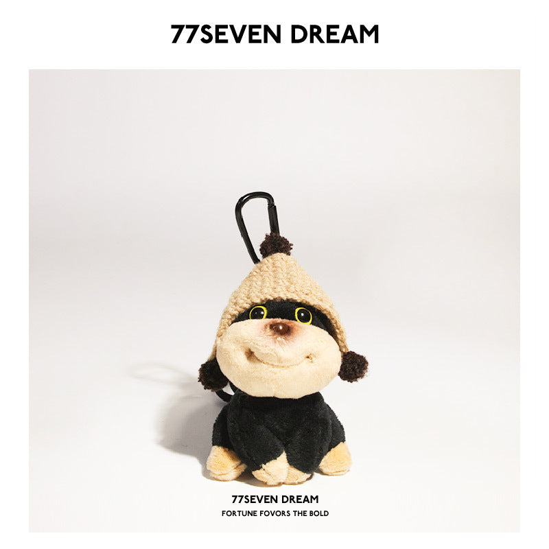 Plush dog keychain charm wearing a khaki knitted hat with brown pompom accents