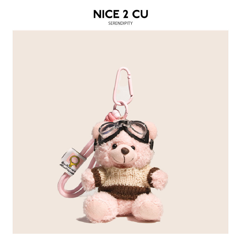 Pink fluffy teddy bear plush keychain wearing a cream and brown striped knit sweater and aviator goggles with pink carabiner 