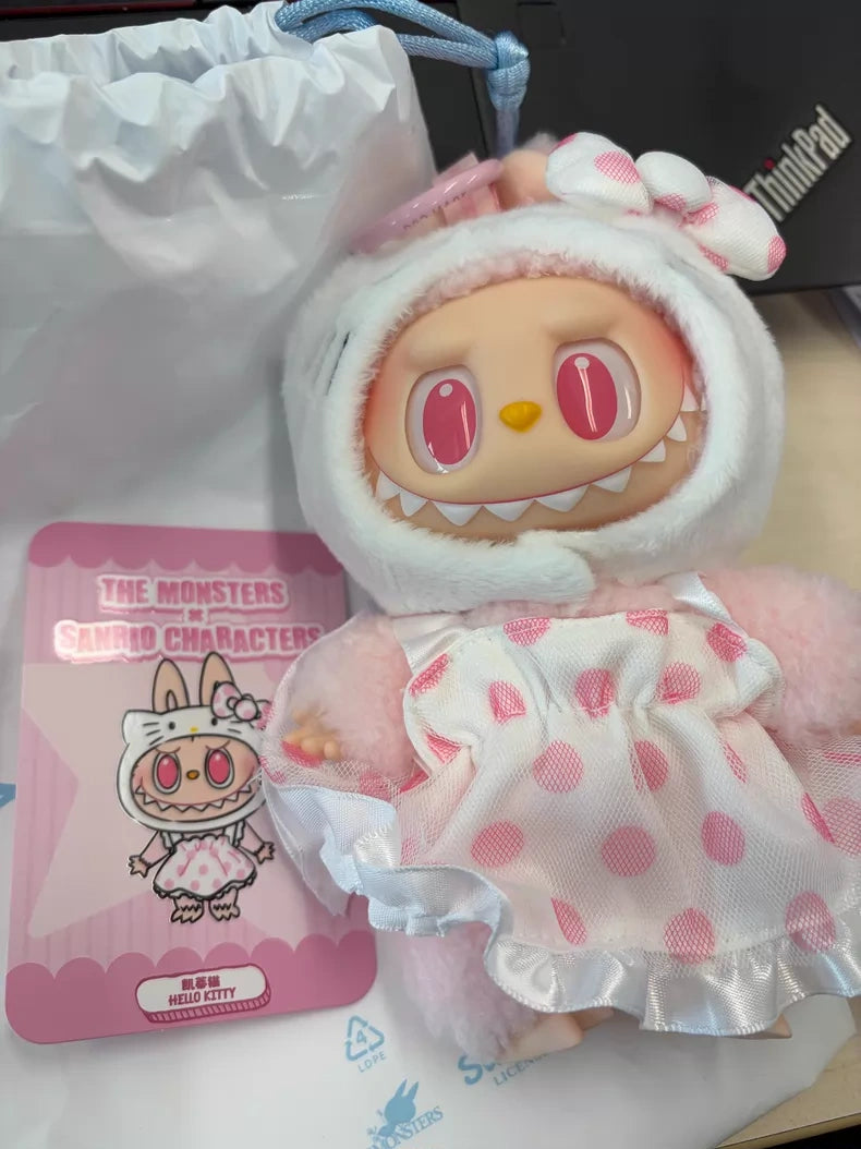 The POP MART LABUBU Hello Kitty and Friends Series Plush Pendant Figure, dressed in a pink polka dot dress and white animal hood, sits beside a collectible The Monsters Sanrio Characters card—ideal for kawaii accessory fans.