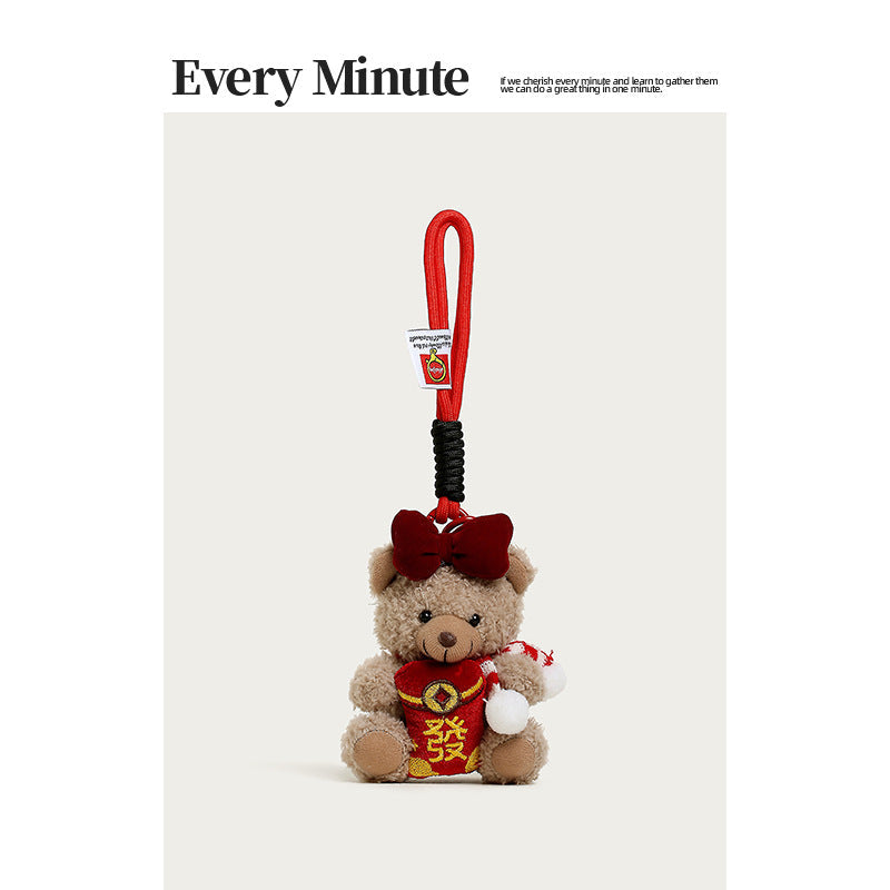 Brown plush teddy bear bag charm with red outfit, gold details, large red bow on head, and festive red-and-white side accesso