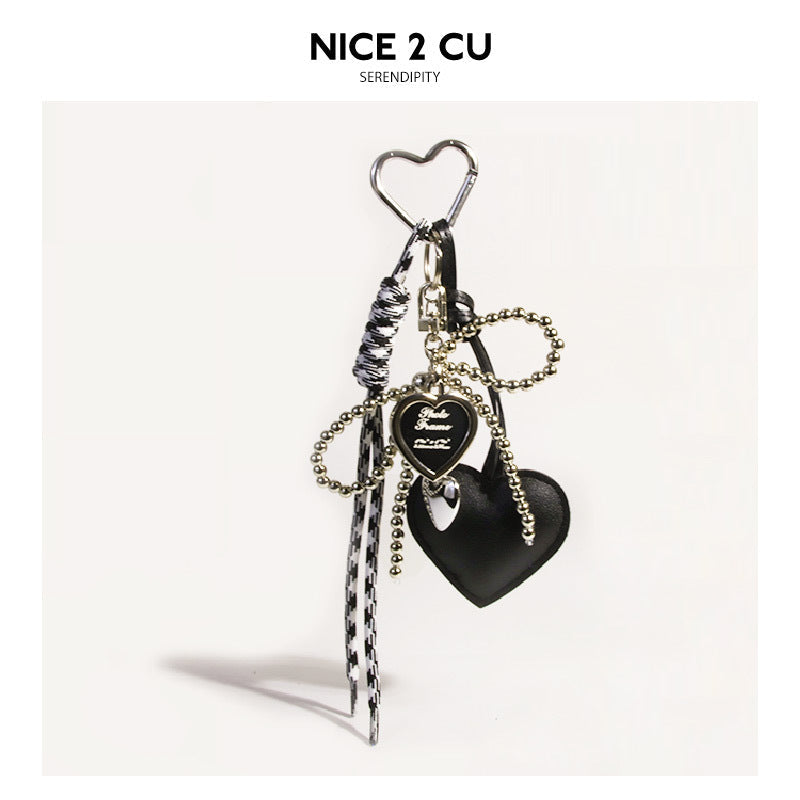 Black heart bag charm with silver heart carabiner, gold bow chain, and houndstooth ribbon tassels