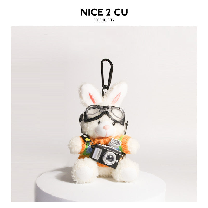 White plush rabbit keychain wearing rainbow-striped knit sweater with aviator goggles and camera pendant