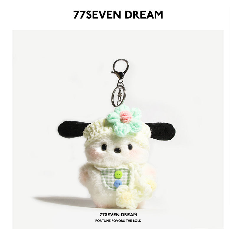 Kawaii dog plush keychain charm with green gingham bib and pink-centered flower hat detail on plain background