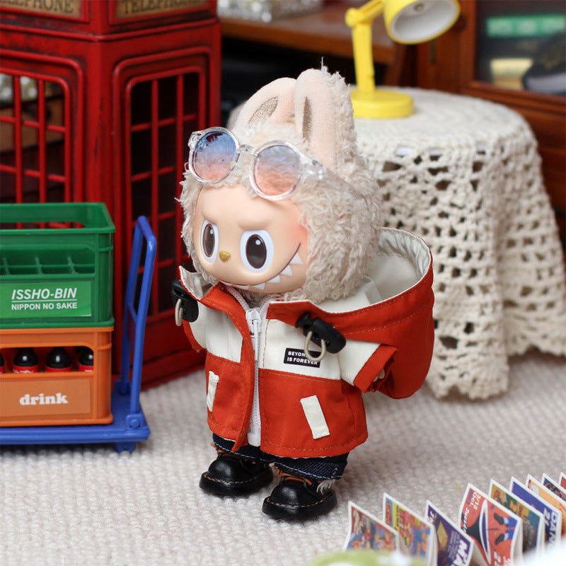 A ZoDoll Labubu plush in the Red Explorer Jacket Outfit Set with gloves and boots stands indoors by a green crate and postcard display on a carpeted floor.