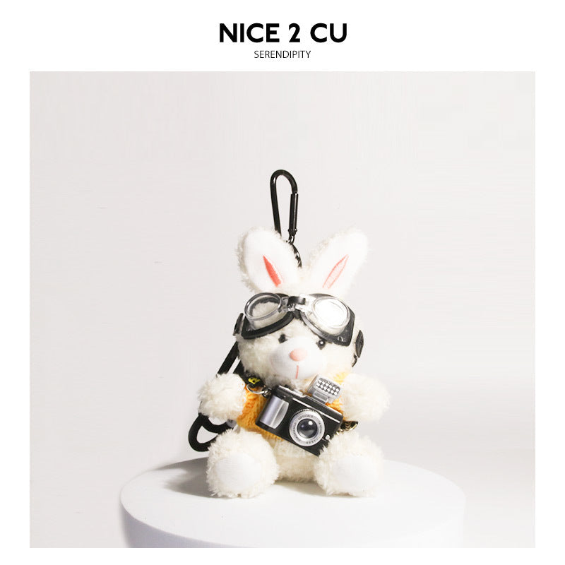 White plush rabbit keychain wearing white-and-yellow knit sweater with aviator goggles and camera