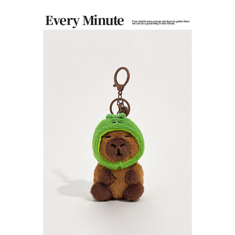 Brown plush capybara keychain wearing a bright green dinosaur hood with metal keyring hardware