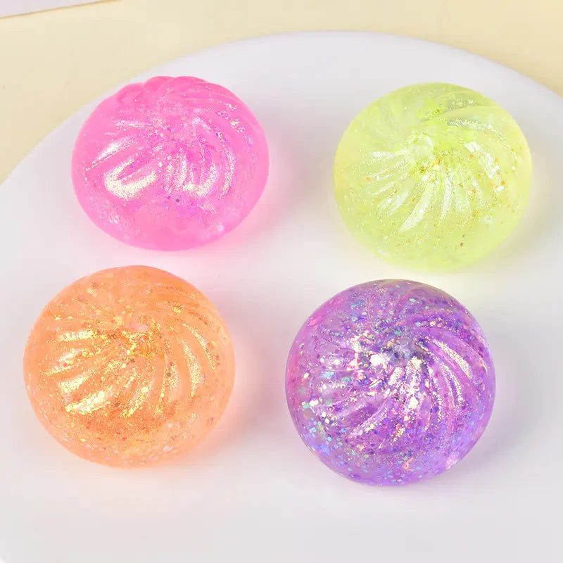 Four glittery, translucent ZoDoll Glitter Squishy Dumpling Sensory Fidget Toys in pink, yellow, orange, and purple are arranged on a white surface with their steamer—perfect for sensory play or stress relief.