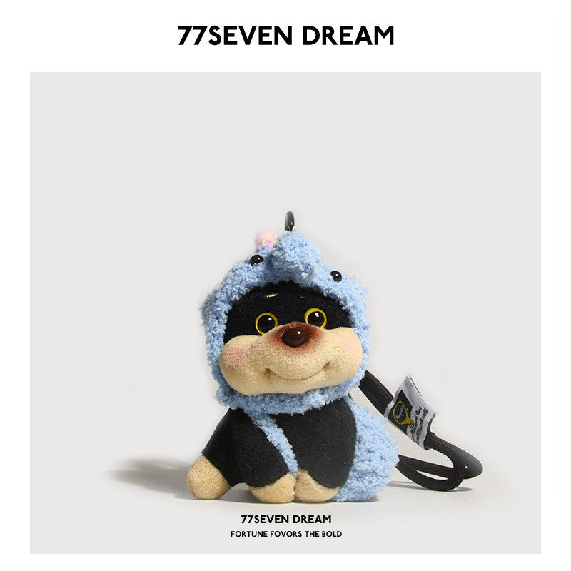 Chubby dog plush charm wearing a light blue elephant hood with trunk-like top detail and a small tag